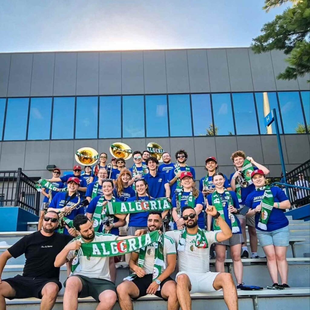 Grupo de torcedores com instrumentos e cachecóis em um estádio, celebrando a doação em Boston.